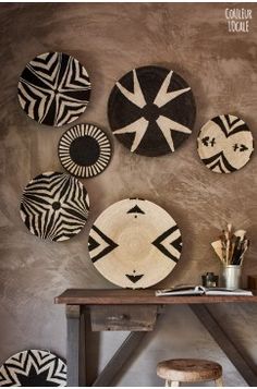 several black and white plates hanging on the wall above a wooden table with stools