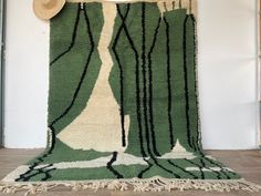 a green and white rug with black lines on the floor next to a hat rack