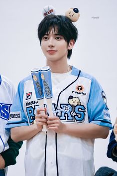 a young man holding two baseball bats in his hands and wearing a jersey with bears on it