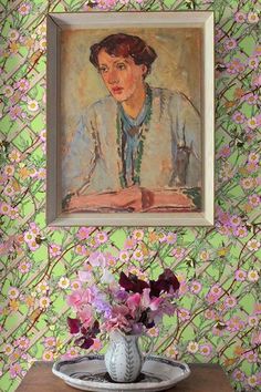 a painting on the wall above a table with flowers