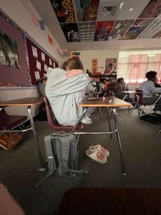 a person sitting at a desk with their back to the camera, wrapped in a blanket