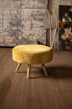 a small yellow foot stool sitting on top of a wooden floor next to a wall