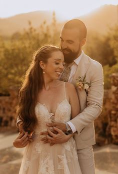 a bride and groom embracing each other outside