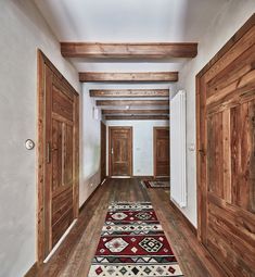 an empty hallway with wooden doors and rugs