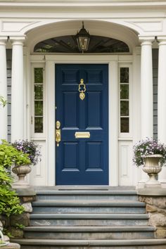 a blue front door with two planters on the steps