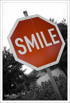 a red and white stop sign with the word smile on it's bottom corner