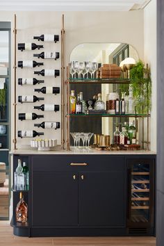 a bar with wine glasses and bottles on the shelves next to an empty glass cabinet