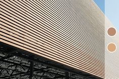 the side of a large building that has three circles on it's face and is brown in color