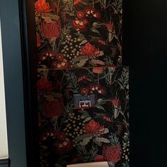 a bathroom with floral wallpaper and a toilet in the corner, next to a light switch