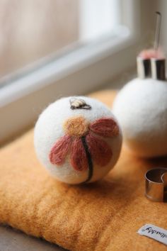 two white balls sitting next to each other on top of a yellow pillow near a window