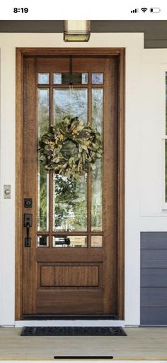 a front door with a wreath on the glass and sidelight is shown in an instagram