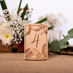 a wooden block with the number four on it next to some flowers and greenery