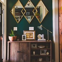 an instagram photo of a living room with green walls and gold mirrors on the wall