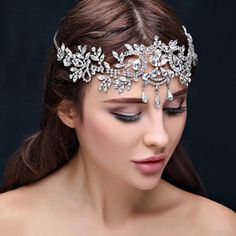 a woman wearing a bridal headpiece with crystal stones and pearls on the side