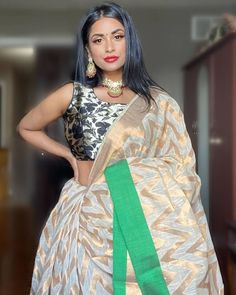 a woman in a white and green sari standing with her hands on her hips