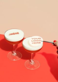 two wine glasses sitting on top of a table with a spoon sticking out of them