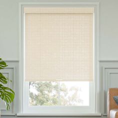 a living room with a couch, chair and window covered in roman shades on the windowsill