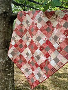 a red and white quilt hanging from a tree