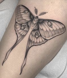 a black and white butterfly tattoo design on the right thigh, with an arrow in the middle