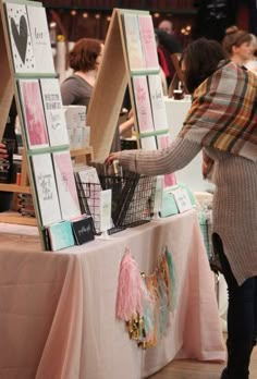 a woman standing next to a table with pictures on it and an easel in front of her