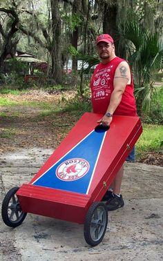 a man in a red shirt is pushing a cart made out of a piece of cardboard