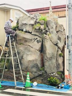 a man on a ladder working on a rock formation