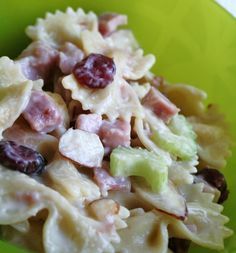 a pasta salad with grapes and celery in a green bowl