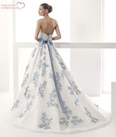 a woman in a white and blue wedding dress looking over a balcony at the ocean