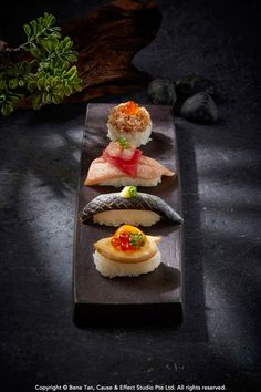 four sushi dishes are arranged on a black plate