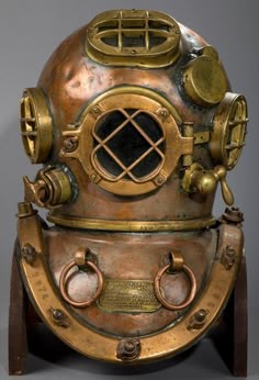 an antique diving helmet on display in front of a gray background with words below it