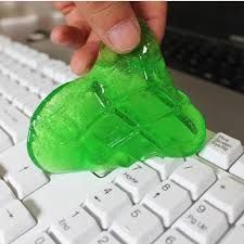 a hand holding a green plastic object over a keyboard