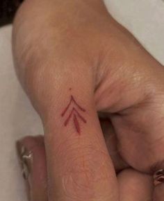 a woman's left hand with a small tattoo on the middle finger and an arrow in the middle