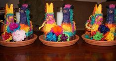 there are three candles that have been made out of colorful yarns and feathers on them