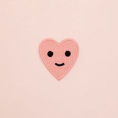 a pink heart with a smiley face on it's left side and black eyes