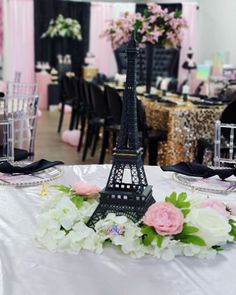 the table is decorated with pink and white flowers in front of the eiffel tower