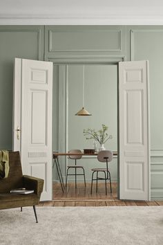 an open door leading to a dining room with two chairs and a table in it