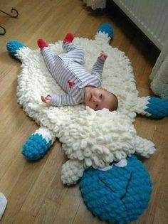 a baby laying on top of a blue and white sheep rug