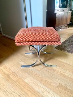 a red and white bench sitting on top of a wooden floor next to a mirror