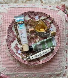 an assortment of beauty products displayed on a pink and white lace doily with pearls