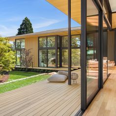 an outdoor living area with wood flooring and large windows on the side of it