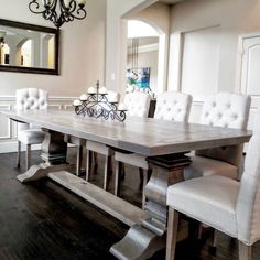 a dining room table with white chairs and a chandelier