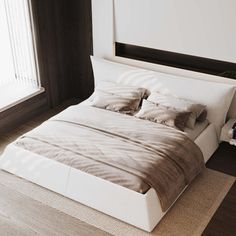 a white bed sitting next to a window in a bedroom on top of a wooden floor