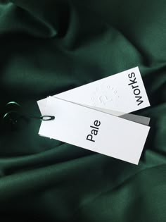 two tags that are sitting on top of a green cloth