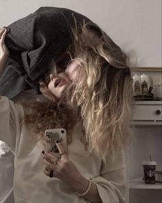 a woman taking a selfie in the mirror with her hair blowing back and holding a cell phone up to her face