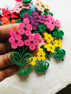 a hand holding a bunch of colorful flowers on top of a white tablecloth covered in crochet