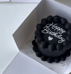 a black birthday cake in a white box with the words happy birthday written on it