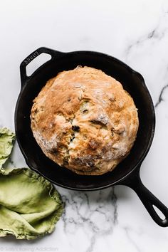 bread in a skillet next to avocado chips on a marble countertop