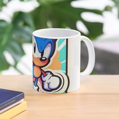 a sonic the hedge mug sitting on top of a wooden table next to a book