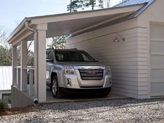 a silver truck parked in front of a white garage with a roof over the car