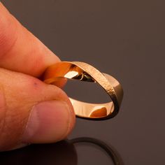 a hand holding a gold ring on top of a table